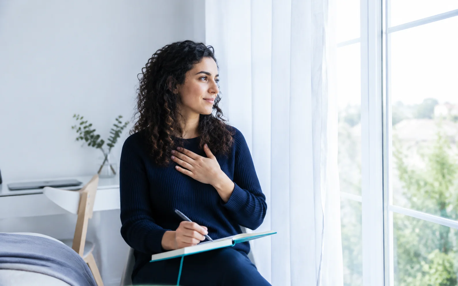 A woman pausing with a journal to reflect on her emotions